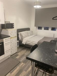 a bedroom with a bed and a kitchen with a table at Exeter Garden for 2 in Ilford