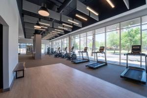 un gimnasio con filas de equipos de ejercicio y ventanas en ASU Sun Devil Luxury Apt, Rooftop Pool & Gym!, en Tempe