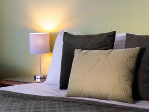 a bed with black and white pillows and a lamp at Wanaka Springs Lodge in Wanaka