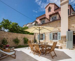 a patio with a table and chairs and an umbrella at Holiday Home City Walls in Hvar