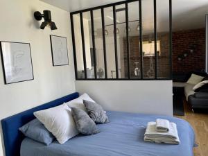 1 cama con sábanas y almohadas azules en una habitación en Idyllique Studio PiscineSPA, Sauna au jardin tropical, en Jouarre
