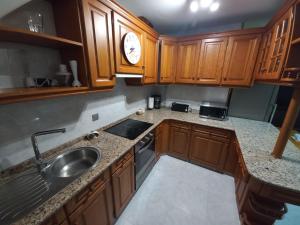 una cocina con armarios de madera y fregadero en Meda hogar, en Caldas de Reis