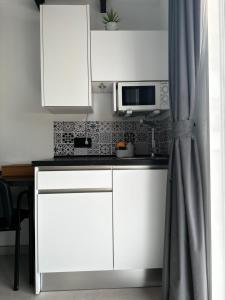 cocina con armarios blancos y microondas en Increíble suite, en Almuñécar