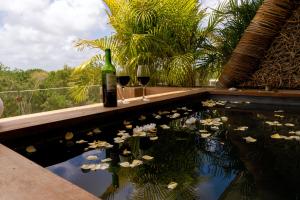 una piscina con dos copas de vino y un estanque de flores en Xamira Tulum Luxury Condo, en Tulum