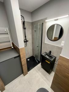 a bathroom with a shower and a sink and a mirror at Studio z balkonem. Słonimskiego 2 in Wrocław