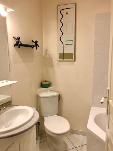 a white bathroom with a toilet and a sink at Villa Elda in Saint-Jean-dʼAngély