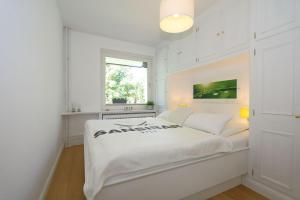 een witte slaapkamer met een wit bed en een raam bij Sylt-to-hus-Alt-Westerland in Westerland