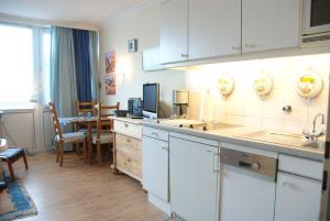 a kitchen with white cabinets and a dining room at App-Kleinhubbert in Westerland (Sylt)