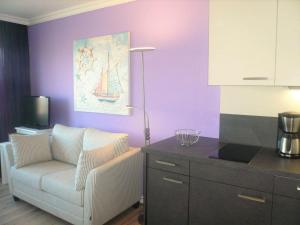 uma sala de estar com uma cadeira branca e uma parede roxa em App-Meinecke-29-O em Westerland