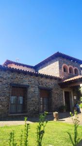 a stone house with a grass yard in front of it at Casa rural Suerte de los Mozos in Cáceres