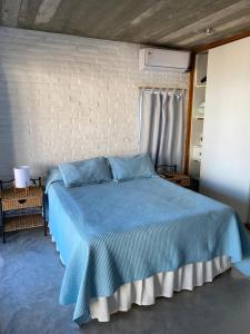 Cama azul en habitación con pared de ladrillo en Miralejos, en Punta del Diablo
