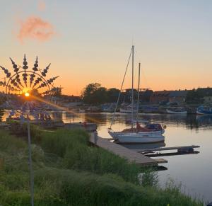a marina with boats and a ferris wheel at sunset at Pāvilostas_laivas in Pāvilosta