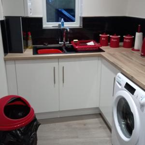 a kitchen counter with a sink and a washing machine at J & S Apartments in Ayr