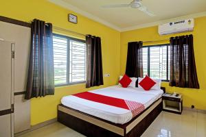 a bedroom with a bed with yellow walls and red pillows at Flagship JMD Upasana 2 in Kolkata