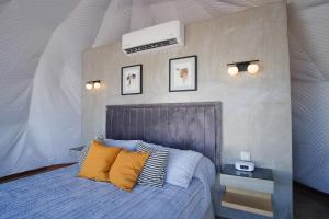 1 dormitorio con 1 cama grande con almohadas amarillas en Cúpulas Del Valle by Villa De La Rosa en Ensenada