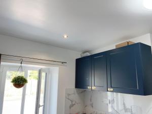 Una cocina con gabinetes azules y una ventana. en La MiMi des Minimes, en La Rochelle