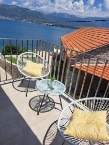 2 Stühle und ein Tisch auf einem Balkon mit Wasser in der Unterkunft Sapore Di Mare Apartment in Tivat
