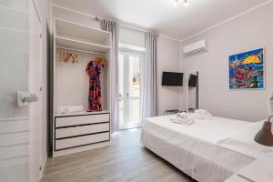 a white bedroom with a bed and a window at LE PORTE DEL KASSARO in Palermo