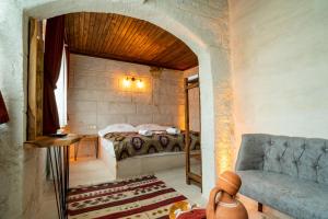 內夫謝希爾的住宿－Cappadocia Snora Cave，一间卧室配有一张床和一个沙发