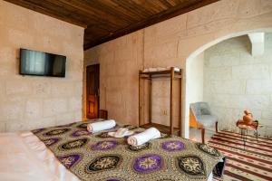 a bedroom with a bed with a tv on the wall at Cappadocia Snora Cave in Nevsehir