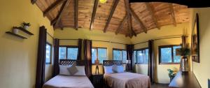 a bedroom with two beds in a room with windows at Cabaña No.10 Puerta del Bosque Mazamitla. in Mazamitla