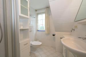 ein weißes Badezimmer mit Toilette und Waschbecken in der Unterkunft App. Inselruhe 8 in Munkmarsch