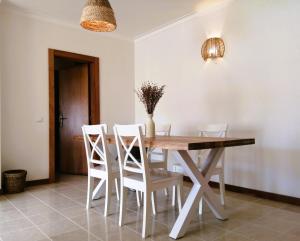 a dining room with a wooden table and white chairs at Nalu House Baleal - by the beach in Baleal