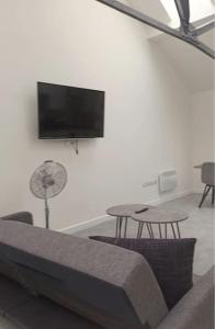Modern Loft Apartment في روثيرهام: غرفة معيشة مع أريكة وطاولة وتلفزيون بشاشة مسطحة