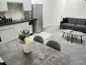 Modern Loft Apartment في روثيرهام: مطبخ وغرفة معيشة مع طاولة عليها زهور