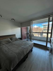 a bedroom with a bed and a large window at Departamento en pucon in Pucón