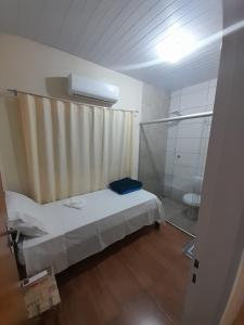 um pequeno quarto com uma cama e um chuveiro em Hostel Casa Uniao em Maracaju