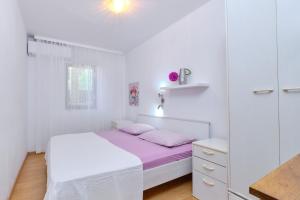 um quarto branco com uma cama com lençóis cor-de-rosa em Apartment Artatore 2509a em Čunski