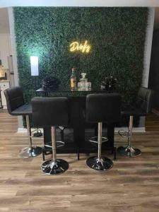 a bar with black chairs in front of a green wall at Beautiful Home In Greenville in Greenville