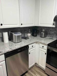 uma cozinha com armários brancos e uma máquina de lavar louça em aço inoxidável em Beautiful Home In Greenville em Greenville