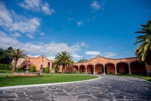 une cour avec des palmiers et un bâtiment dans l'établissement Hotel Hacienda La Cieneguita, à San Miguel de Allende