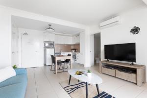 a living room with a blue couch and a tv at Aspect Caloundra in Caloundra