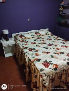 Una cama en un dormitorio con una manta floral. en M&Cmdq, en Mar del Plata