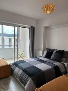 een slaapkamer met een bed en een groot raam bij Chambre proche mer et aeroport in Nice