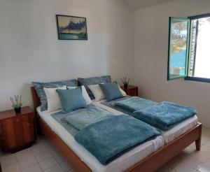 a bed with blue pillows on it in a room at Secluded fisherman's cottage Lavdara, Dugi otok - 21569 in Sali +7 photos