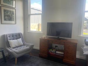 a living room with a chair and a flat screen tv at Alloa Petite in Fernside