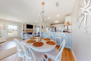 a kitchen and dining room with a white table and chairs at Compass Rose in Topsail Beach