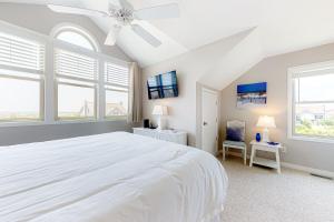 a white bedroom with a large white bed and windows at Compass Rose in Topsail Beach