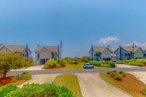 un coche conduciendo por una carretera en un barrio residencial en Compass Rose en Topsail Beach