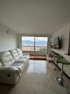 sala de estar con sofá blanco y TV en Hermosa vista a la ciudad de Medellín, en Medellín
