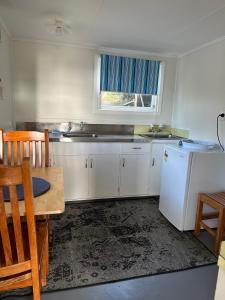 a kitchen with white cabinets and a table and a window at 58 Pioneer - Retro Studio Unit in New Plymouth +4 photos