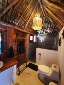 bagno con servizi igienici bianchi e lampadario pendente. di Casa Sofia Holbox a Isola Holbox