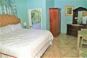 a bedroom with a bed and a table and a door at Dela de-Rose Guest House Negril Jamaica in Negril