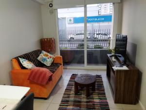 ein Wohnzimmer mit einem Sofa, einem TV und einem Tisch in der Unterkunft Acogedor departamento en Temuco in Temuco