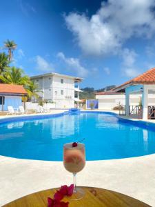 a drink on a table in front of a swimming pool at Hotel Candy Rose in Colón