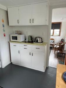 a kitchen with white cabinets and a microwave at 58 Pioneer - Retro Studio Unit in New Plymouth